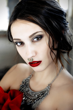 Beautiful woman with cute face bright make up red lips and piercing on noseの写真素材
