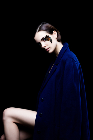 Young pretty woman face with false feather eyelashes fashion makeup wearing blue coatの写真素材