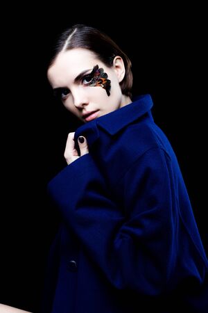Young pretty woman face with false feather eyelashes fashion makeup wearing blue coatの写真素材