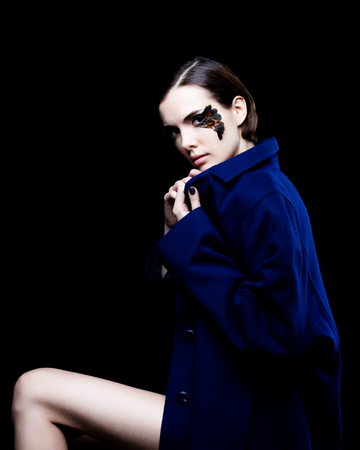 Young pretty woman face with false feather eyelashes fashion makeup wearing blue coatの写真素材