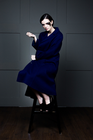 Young pretty woman face with false feather eyelashes fashion makeup wearing blue coatの写真素材