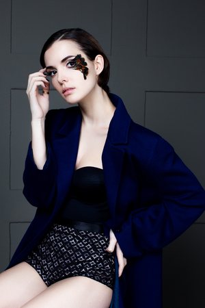 Young pretty woman face with false feather eyelashes fashion makeup wearing blue coatの写真素材