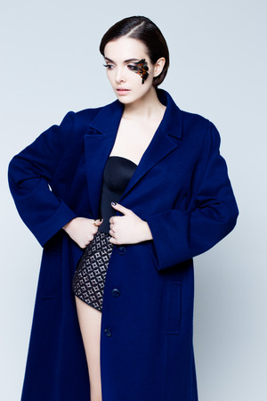 Young pretty woman face with false feather eyelashes fashion makeup wearing blue coatの写真素材