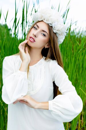 Beautiful sexy woman face wearing floral white wreath outdoorsの写真素材