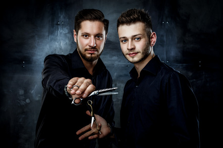 Elegant young handsome men. Man with straight razor and man holding hairdressers scisorsの写真素材