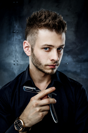 Elegant young handsome man. Studio fashion portrait.Portrait of a young brutal man with straight razorの写真素材