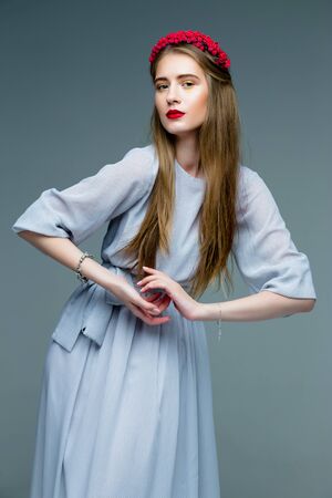 Beautifull female model long-haired woman wearing dress and red wreath with red lipsの写真素材