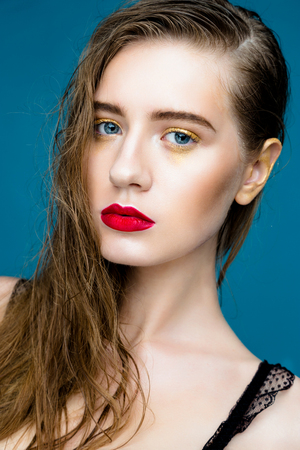 Beauty fashion girl. Portrait of beautiful young woman with fresh clean skin and red lips on blue backgroundの写真素材