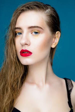 Beauty fashion girl. Portrait of beautiful young woman with fresh clean skin and red lips on blue backgroundの写真素材