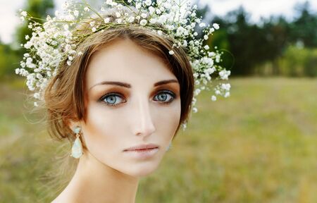 Close up portrait of woman face wearing floral white wreath outdoorsの写真素材