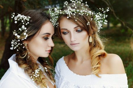 Two women in white dresses with flowers outdoorsの写真素材