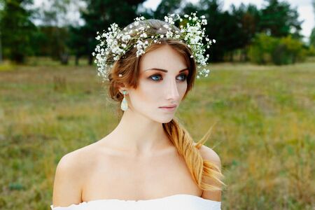 Close up portrait of woman face wearing floral white wreath outdoorsの写真素材