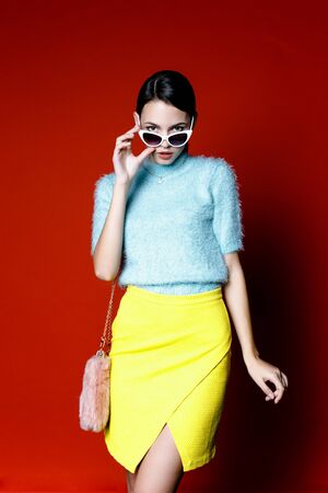 Cute young woman wearing blue and yellow cloth on red backgroundの写真素材