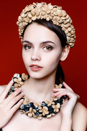 Portrait of pretty young woman with beads on red backgroundの写真素材