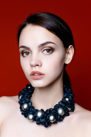 Portrait of pretty young woman with beads on red backgroundの写真素材