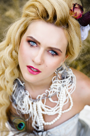 Blonde woman with long curly hair with flower accessory in antique corset and underwearの写真素材