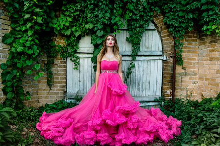 Beautiful woman in gorgeous pink dress outdoors. Full length Portrait.の写真素材