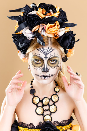 attractive young woman with sugar skull makeup, Dia de los Muertos - Mexican Day of the dead woman wearing sugar skull makeup and flower wreath.の写真素材