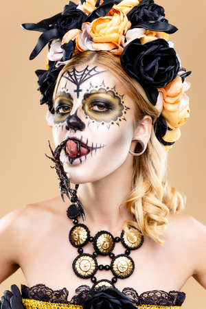attractive young woman with sugar skull makeup, Dia de los Muertos - Mexican Day of the dead woman wearing sugar skull makeup and flower wreath.の写真素材