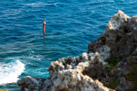 Blue Okinawa ocean on sunny day with rock cliffの写真素材
