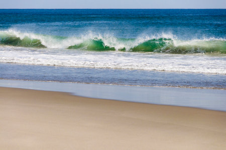Waves breaking on the sandy beach on a hot summer day.の写真素材