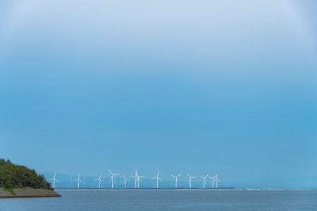 Wind turbines on the sea shore under a blue sky with clouds. Lake Jusan, Nakanoshima Island and...