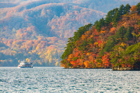 Autumn leaves and sightseeing boats at Lake Towada, Japan