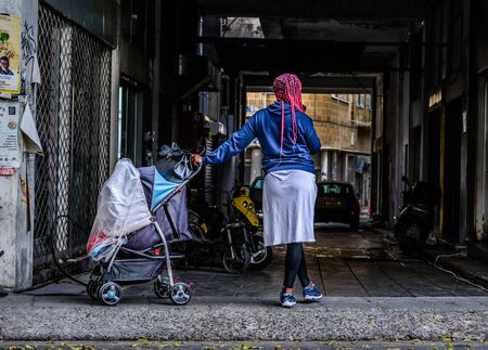 A black woman is standing on the street with her baby in the strollerのeditorial素材