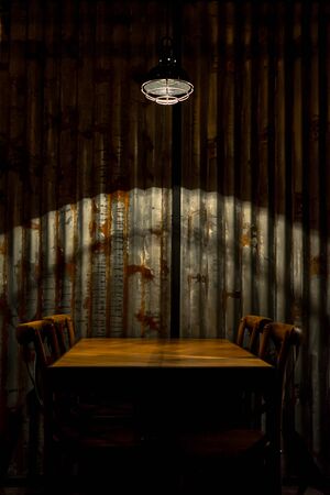 A table with chairs under a light in a restaurantのeditorial素材