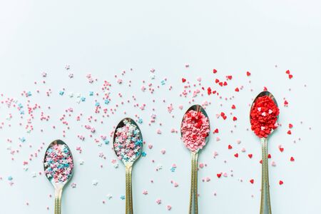Metal spoons with colored confectionery powder on a white backgroundの写真素材
