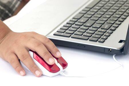 Human hand on computer mouse and Laptop on deskの写真素材