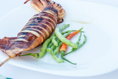 Fresh grilled squid with spicy on plate on white background
