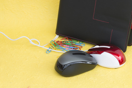 Wireless mouse with notebook and paper clip on yellow backgroundの写真素材