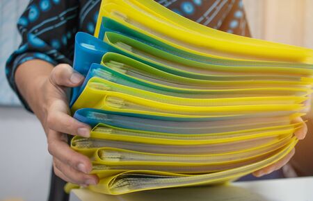 Asian Businesswoman holding many documents Stacks of folders in office for Annual Report files,...