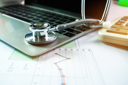 Stethoscope with prescription test results in Doctor consulting room background and calculator for...