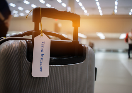 Travel Insurance tag on suitcase holder with tag tied letters enjoyable your trip on bag. Travel Insurance is intended cover medical expenses, cover lost luggage, flight cancellation or accident.の写真素材