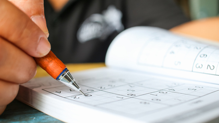 Student  is trying to solve sudoku with color pencil as hobby at outdoor の写真素材