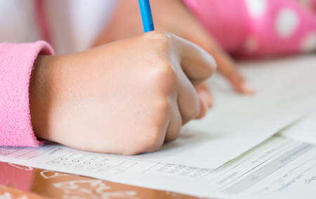 Students concentration holding pencils in hand doing multiple-choice quizzes testing exams answer sheets exercises in school, Tests is concept assessment intended to measure knowledge skill aptitudeの写真素材