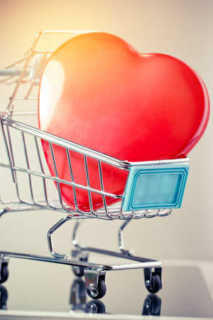 Endless love Valentine's day concept, Red heart in shopping cart, basket supermarket on screen tablet background. Love is passion for romantic couple and Connection, Celebration of world wide to knowの写真素材