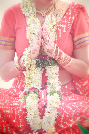 bride hands in namaste with wedding indian floral garlandの写真素材