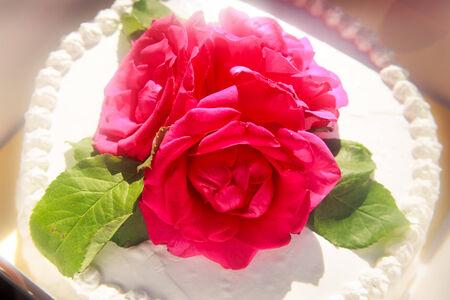 three red roses on the top of white creamy delicious cake closeupの写真素材