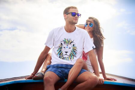 attractive brunette girl with her boyfriend wear sunglases and sit on longtail boatの写真素材