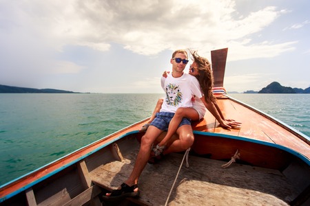attractive brunette girl with her boyfriend sit on longtail boat in Thailandの写真素材
