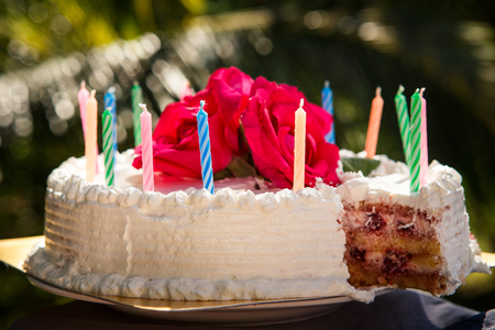 one piece of white creamy delicious cake decorated with candles and three red roses on the topの写真素材