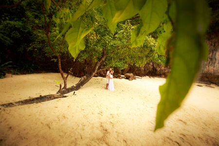 groom embracing his bride with his arms round her waist and their fingers in wedding rings interlacedの写真素材