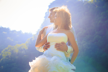 blonde bride and handsome groom stand on longtail boat in Thailandの写真素材