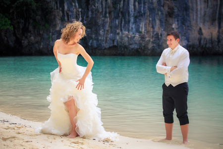 blonde bride and handsome groom stand near blue sea water on island beach Thailandの写真素材