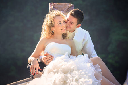 blonde bride and handsome groom sit on longtail boat in Thailandの写真素材