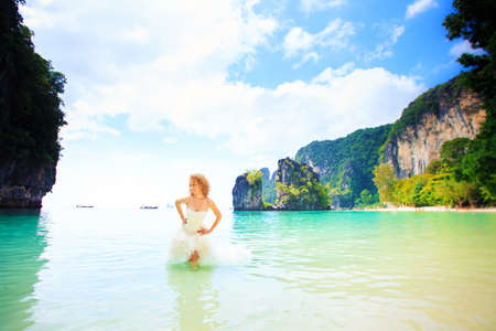 blonde bride in elegant wedding dress pose standing in sea water in Thailandの写真素材