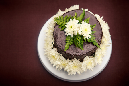 chocolate delicious cake decorated with white flowers and green leafsの写真素材
